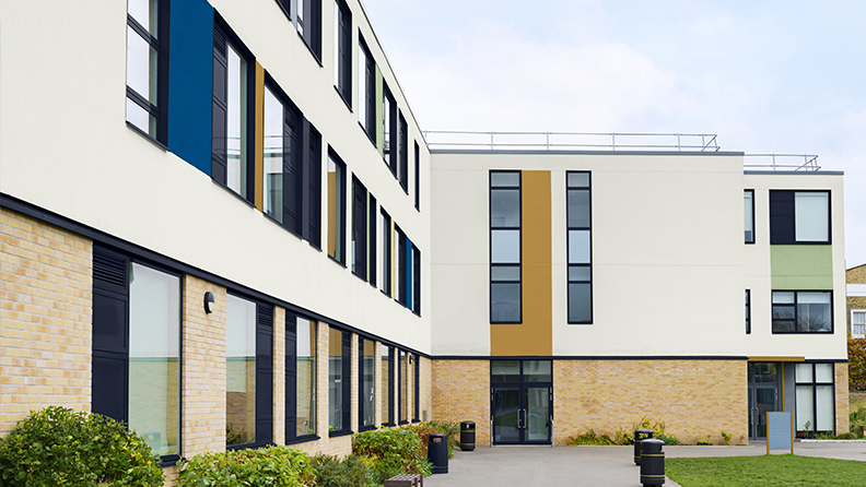 Fassadenansicht einer Schule mit Farbblöcken auf neutraler Fassade