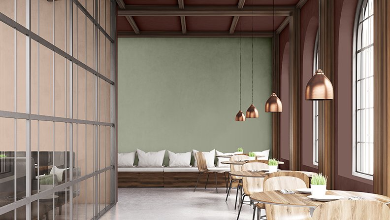 Hotelrestaurant mit grüner Akzentwand und bronzefarbenen Pendelleuchten