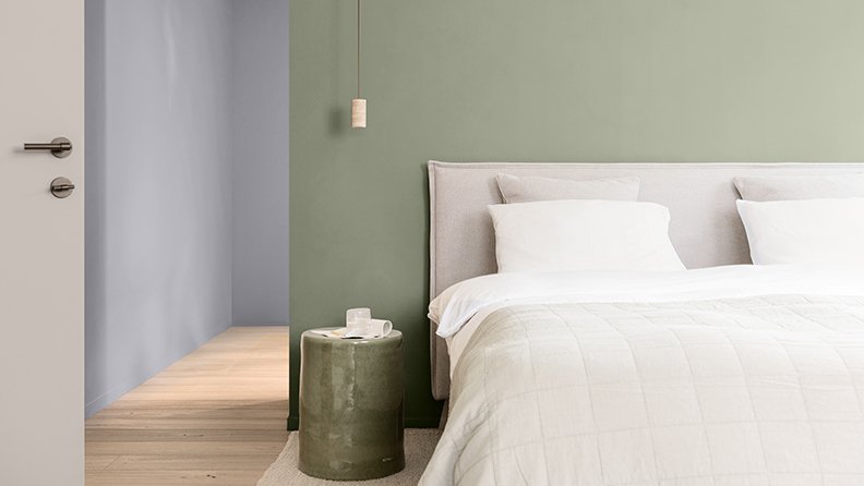 Hotelzimmer mit grüner Akzentwand und sanft brauner Tür