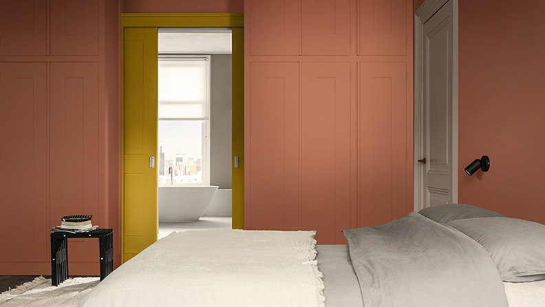 Ein warmes und gemütliches Hotelzimmer, gestrichen in Terrakotta-Rot und leuchtendem Gelb