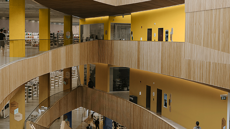 Eine moderne Bibliothek, die sich über mehrere Etagen erstreckt Gelbe Wände heben sich von der Holzvertäfelung ab