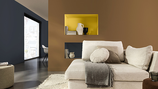 Dunkelbraune Wand mit gelber Akzentfarbe und einem weißen Sofa