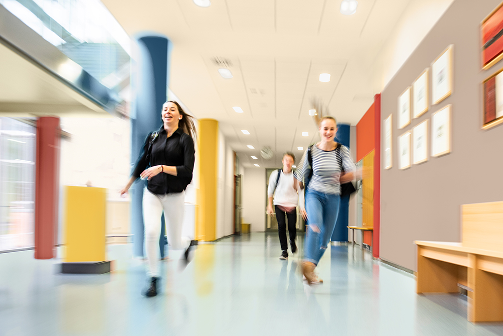 Student running through a school hallway with walls painted in bright colours