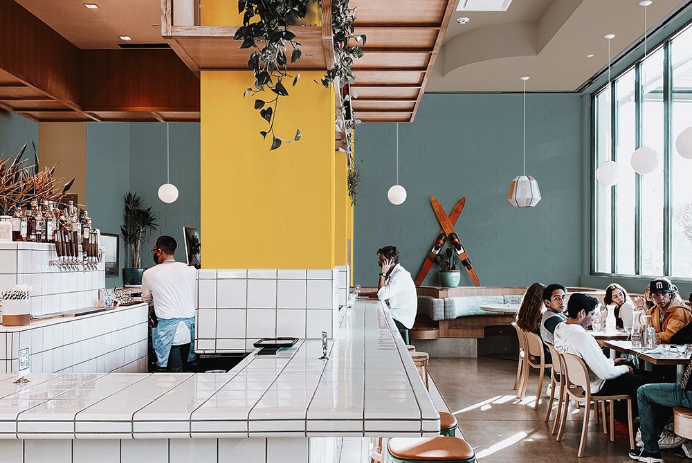 Restaurant with large yellow pillar and white-tiled bar