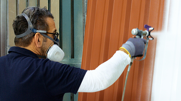 Maler spritzt Lack auf ein Metalltor