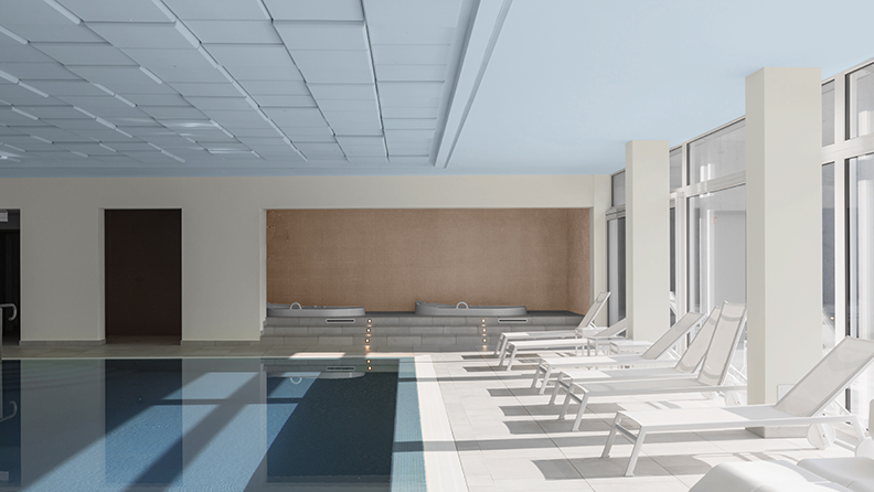 Hotelschwimmbad mit weißen Liegen und blauer Decke
